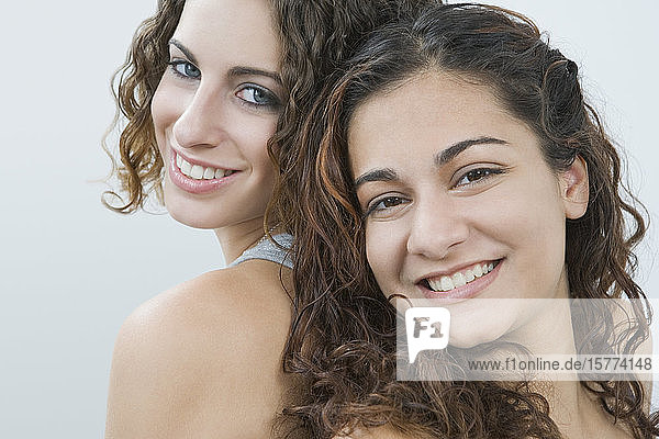 Portrait of two teenage girls smiling back to back
