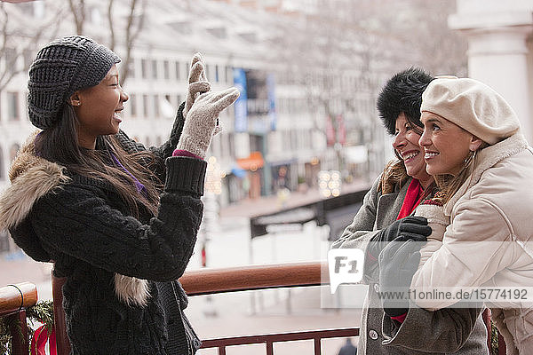 A woman taking a picture of two friends outside during the Christmas season; Boston  Massachusetts  United States of America