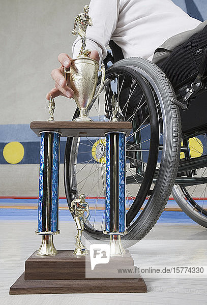 Mittelansicht eines behinderten Mannes  der in einem Rollstuhl sitzt und eine Trophäe hält