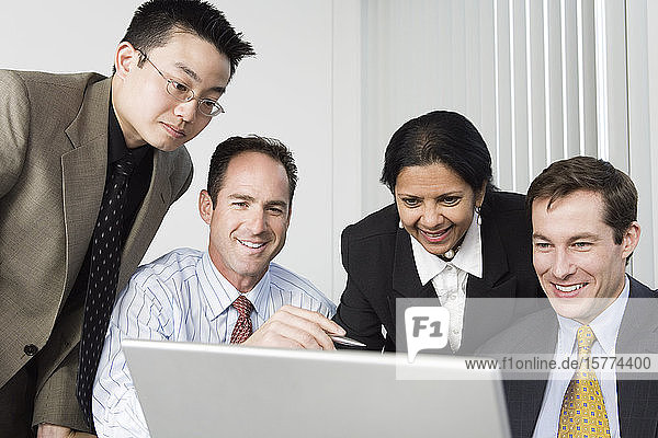 Geschäftsleute schauen auf einen Laptop.