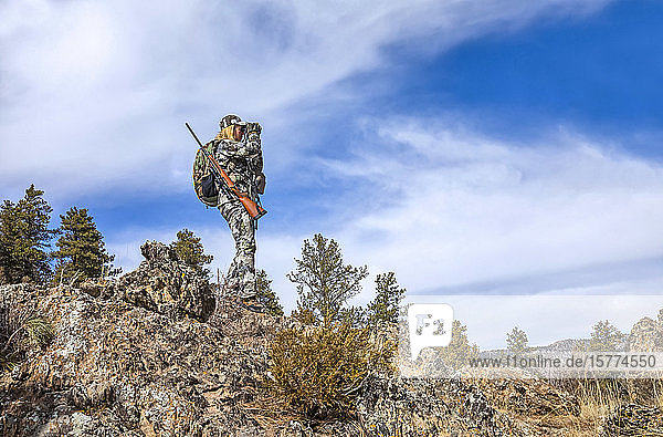 Jäger mit Tarnkleidung und Gewehr  der mit einem Fernglas hinausschaut; Denver  Colorado  Vereinigte Staaten von Amerika