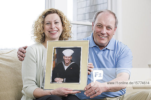 Porträt eines reifen Paares  das ein Bild seines Sohnes hält  der beim Militär arbeitet.