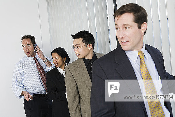 View of businesspeople standing near windows in the office.
