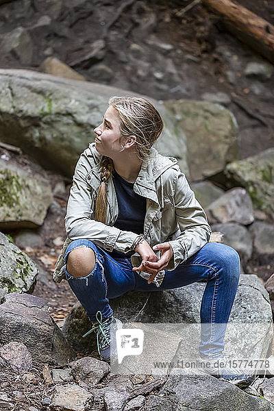 Portrait of a pre-teen girl sitting on rocks in a rocky area in a park; Salmon Arm  British Columbia  Canada