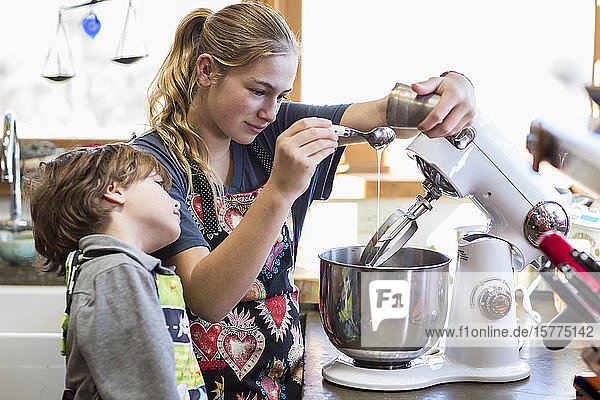 Eine Teenagerin und ihr 6-jähriger Bruder in einer Küche  mit einer Rührschüssel
