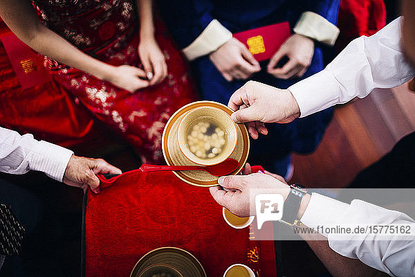Nahaufnahme eines Rituals bei einer chinesischen Hochzeitszeremonie  bei der Menschen eine Schüssel Suppe reichen.