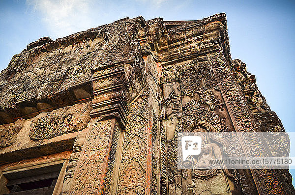 Ankor Wat  ein historischer Khmer-Tempel aus dem 12. Jahrhundert und UNESCO-Weltkulturerbe. Bögen und gemeißelter Stein mit großen Wurzeln  die sich über das Mauerwerk ausbreiten.