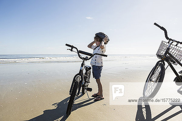 A boy putting on a cycle helmet on the beach  St. Simon's Island  Georgia