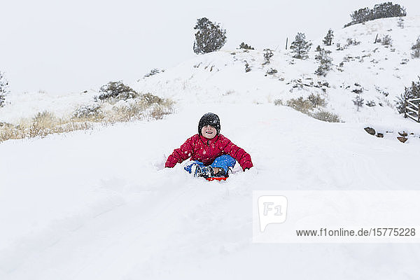 Ein Junge und ein Mädchen rodeln im Schnee den Berg hinunter