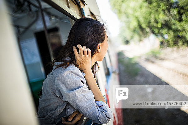 Junge Frau in einem Zug  die aus dem Fenster schaut.