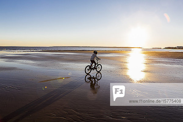 Ein Junge fährt Fahrrad am Strand