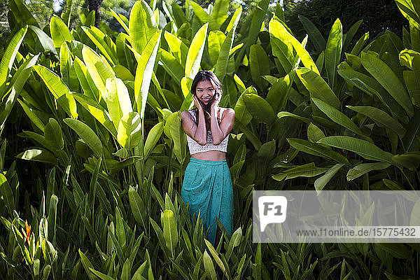Junge Frau steht im Regenwald mit üppig grünem Laub.