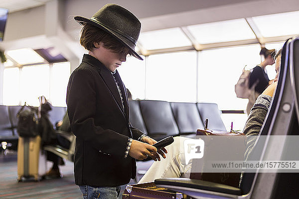 A young boy looking at his briefcase in airport