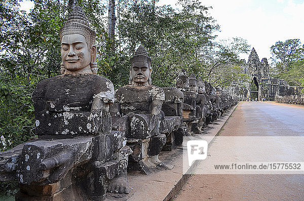 Ankor Wat  ein historischer Khmer-Tempel aus dem 12. Jahrhundert und UNESCO-Weltkulturerbe. Büsten und Statuen von Gottheiten und Wächterfiguren entlang eines Weges zu einer Stupa und einem Eingangsbogen.