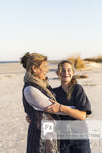Eine Mutter und ihre Tochter umarmen sich am Strand