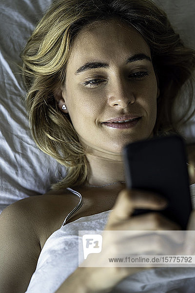 Young woman using smartphone on bed