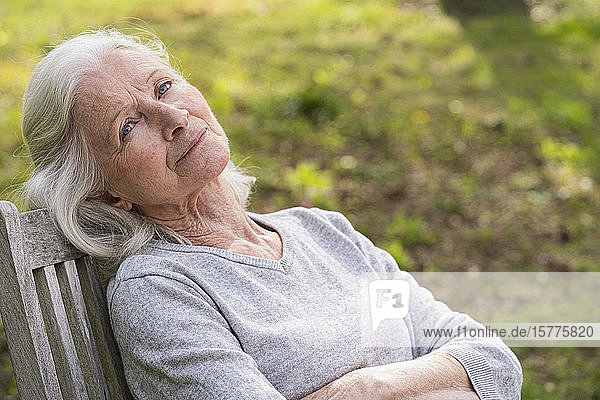 Nachdenkliche ältere Frau entspannt sich im Garten