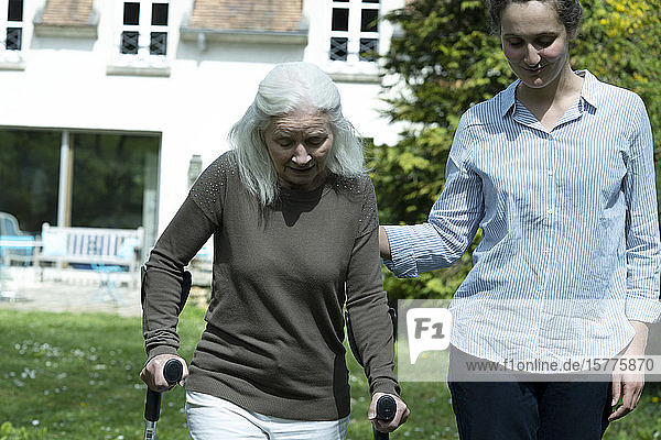 Carer and senior woman walking in garden