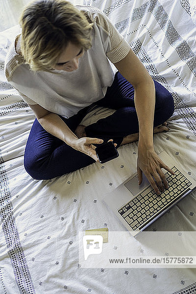 Frau mit Laptop auf dem Bett