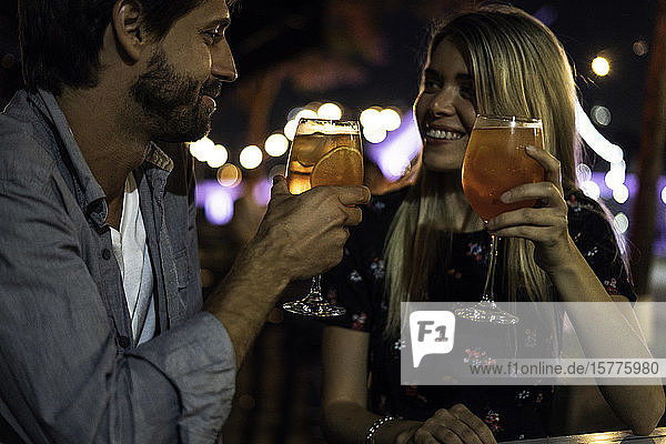 Junges Paar mit Cocktailgläsern in einem Straßencafé