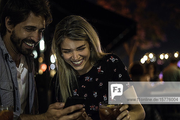 Junges Paar benutzt Smartphone in einem Straßencafé