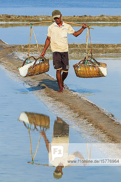 Man with shoulder pole harvesting the salt fields around the Praek Tuek Chhu River estuary south of the city Kampot Cambodia Indochina Southeast Asia Asia