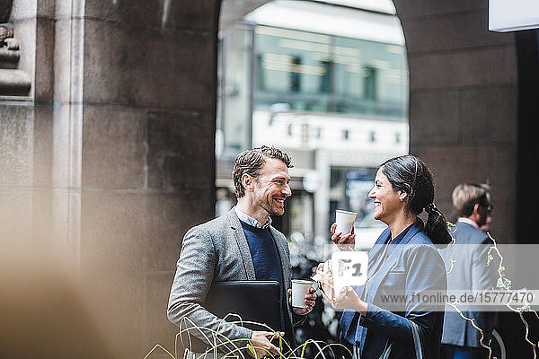 Glückliche Geschäftsleute mit Kaffee im Straßencafé