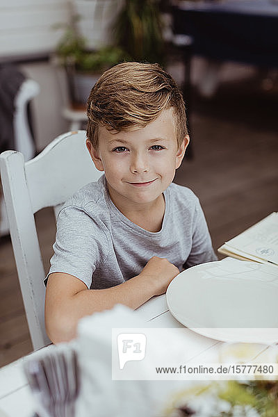 Porträt eines lächelnden Jungen  der am Tisch im Restaurant sitzt