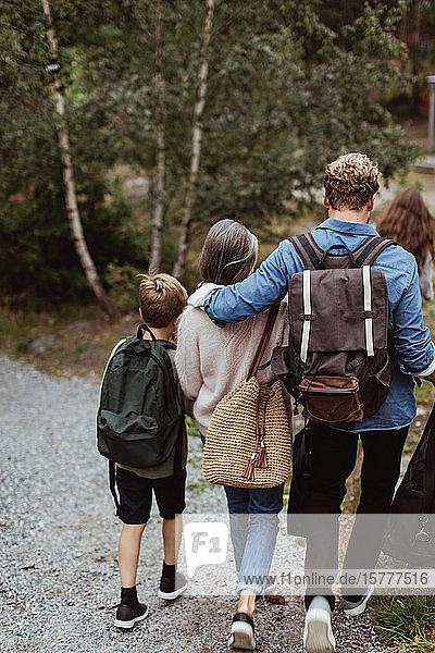 Rückansicht einer Familie mit Rucksack auf einem Wanderweg im Wald