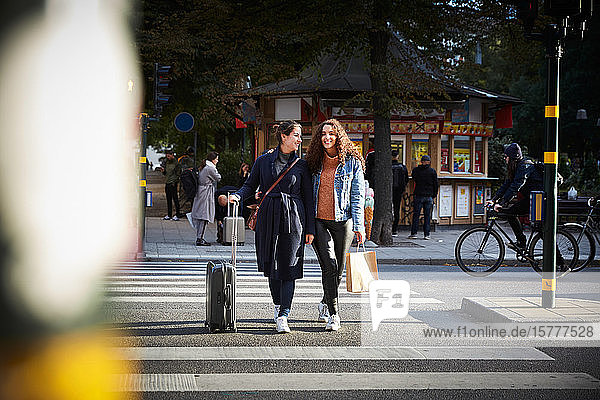 Frauen mit Taschen in voller Länge auf Zebrastreifen in der Stadt