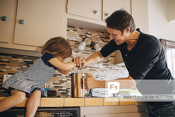 Reifer Vater und Tochter kochen zu Hause Kaffee in französischer Presse