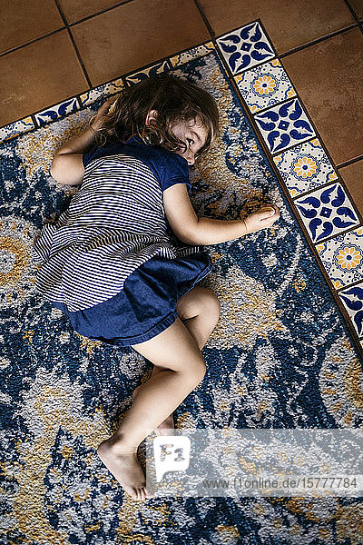 Hochwinkelansicht eines auf dem Teppich liegenden Mädchens