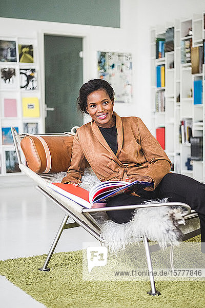 Porträt einer selbstbewussten Architektin mit Buch auf einem Sitz im Home-Office