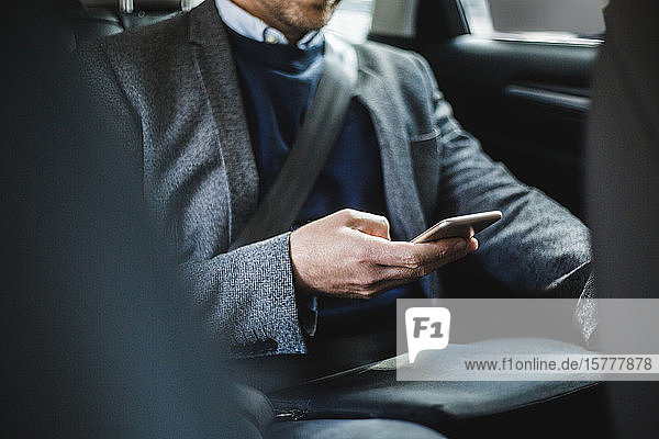 Midsection of mature businessman using phone while sitting in car