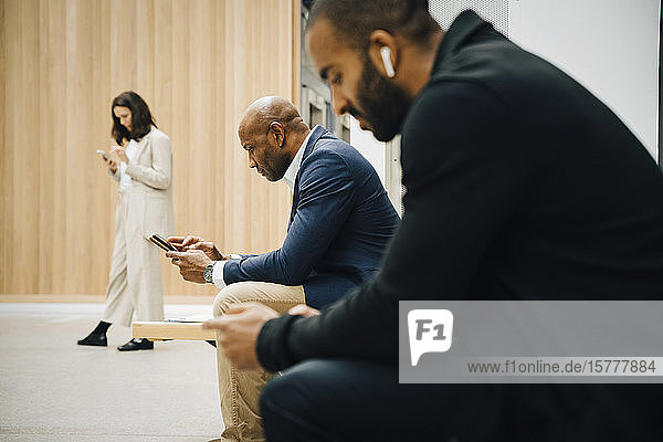 Male and female entrepreneurs using smart phone outside office