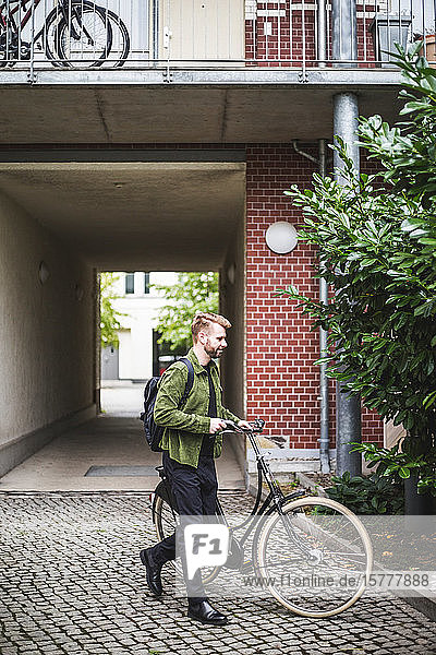 Männlicher Unternehmer mit Fahrrad auf Fußweg