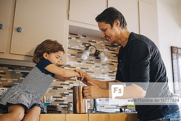 Mature father and daughter working with french press coffee maker in kitchen
