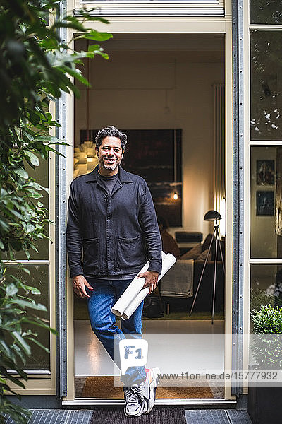 Porträt eines lächelnden  reifen Architekten mit Blaupause in der Tür