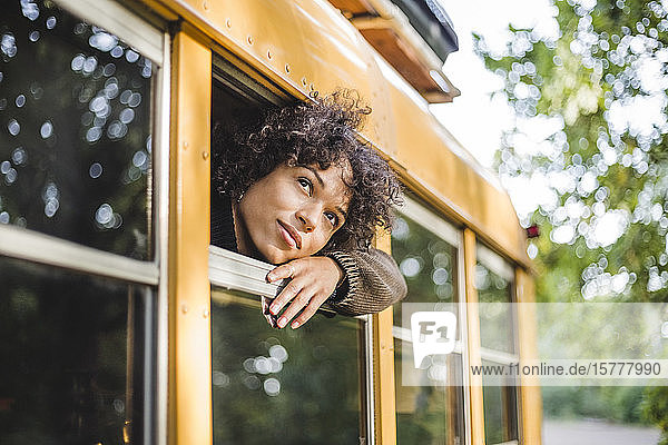 Thoughtful young woman looking through camper vehicle window during camping in forest