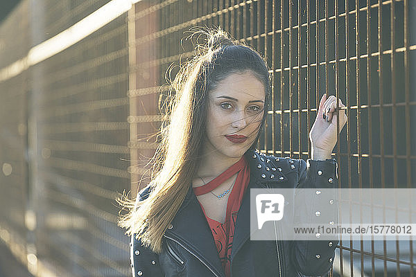 Woman wearing leather jacket holding metal fence
