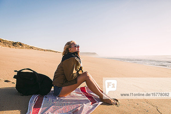 Woman sitting on towel on beach
