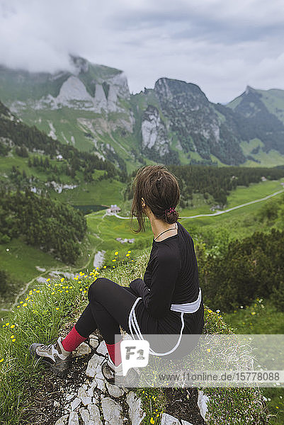 Frau sitzt auf einem Felsen in den Bergen in Appenzell  Schweiz