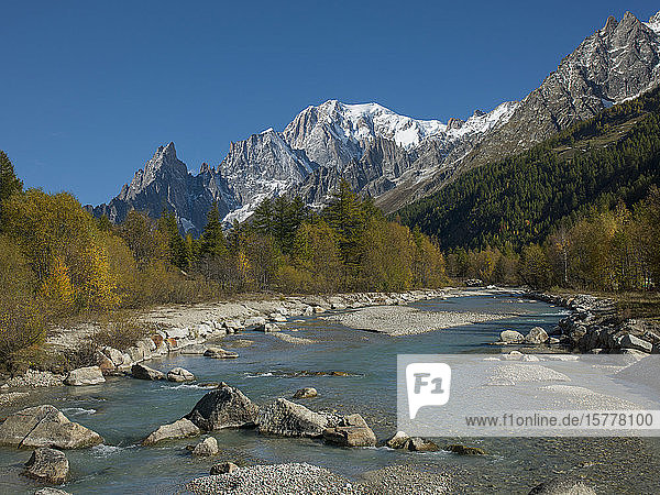 Snowcapped mountain by river in Aosta Valley Italy