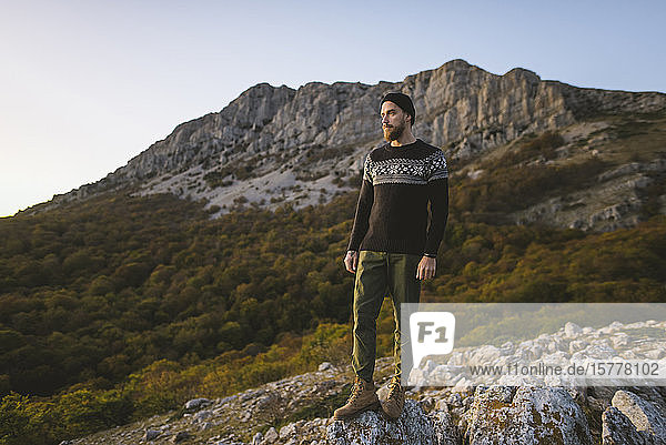 Mann steht auf einem Felsen am Berg