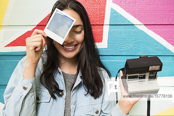 Lächelnde Frau mit Foto und Polaroidkamera