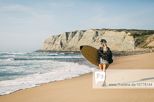 Frau hält Surfbrett am Strand