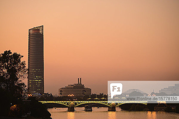 Triana Bridge in front of Sevilla Tower at sunset in Seville Spain