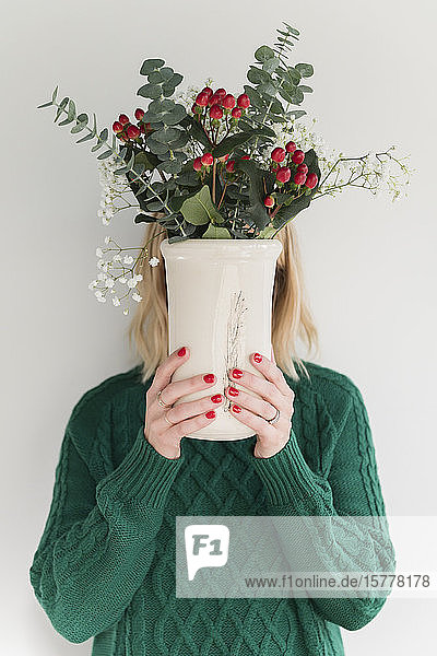 Woman wearing green holding vase of flowers