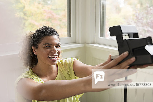 Smiling woman taking selfie with Polaroid camera
