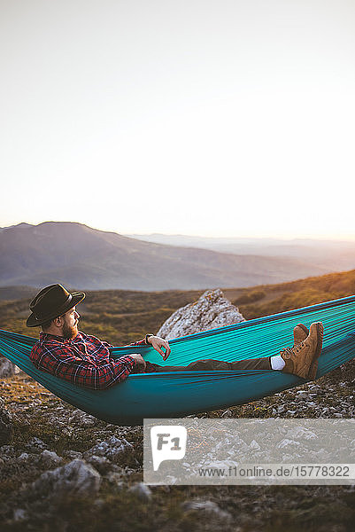Man lying on hammock in mountain range